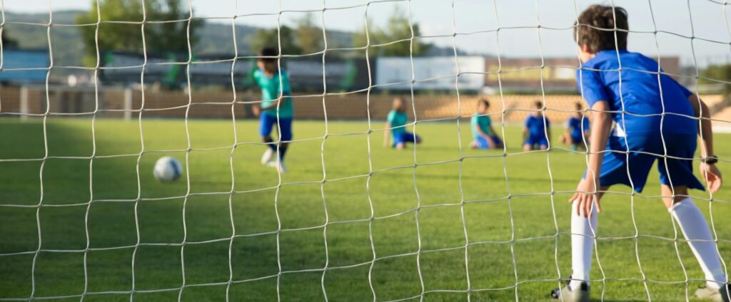 Kids enjoying a soccer match on a sunny day in Portugal with clear blue skies.